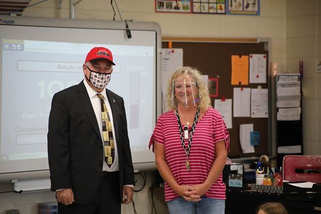 Superintendent Woods poses for the photo with a teacher in her classroom. Both are facing the camera. Superintendent Woods is wearing a face mask while the teacher is wearing a transparent face shield and smiling.
