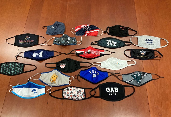 A photo of 19 masks received by the Superintendent during his visits to schools throughout Georgia. Each mask is spread out to show each school’s logo, which is printed across the front.